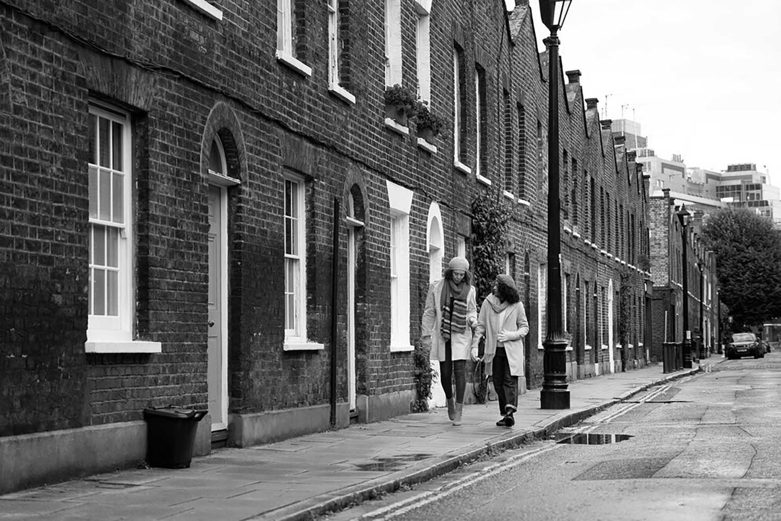 full-shot-women-walking-city_23-2149142290 Two people walking along a historic brick street in London, lined with traditional townhouses.