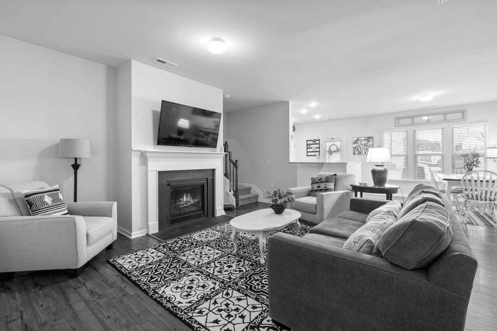 pexels-curtis-adams-1694007-7027764 Cozy living room with fireplace, TV, and comfortable seating, leading to a bright dining area.