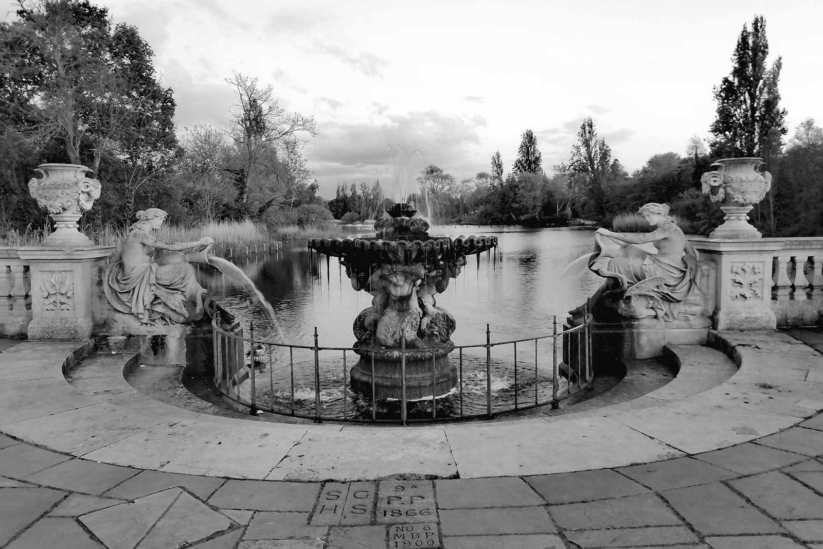 pexels-happy-aura-436491182-22574831 Ornate fountain with statues in a serene garden setting, surrounded by trees and water.
