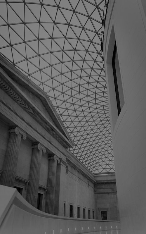 Interior of a modern atrium with a geometric glass roof and classical architectural elements.